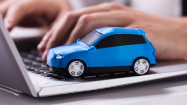 small blue model car sitting on laptop keyboard
