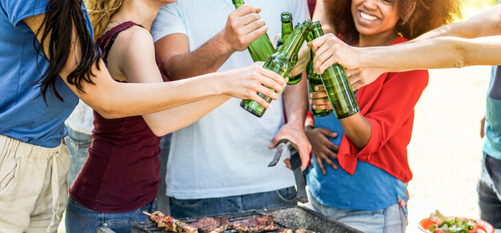 group of friends drinking beer around a barbecue