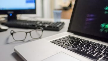 laptop and eyeglasses sitting on desk