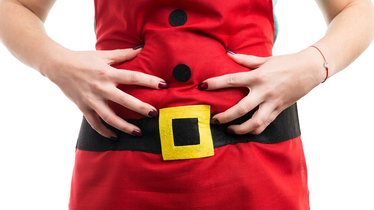 woman dressed as santa holding bloated stomach