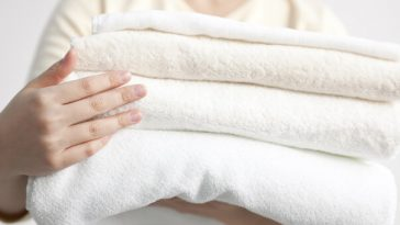 hands carrying stack of white towels