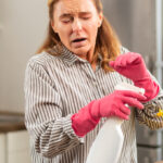 woman sneezing while cleaning kitchen allergens