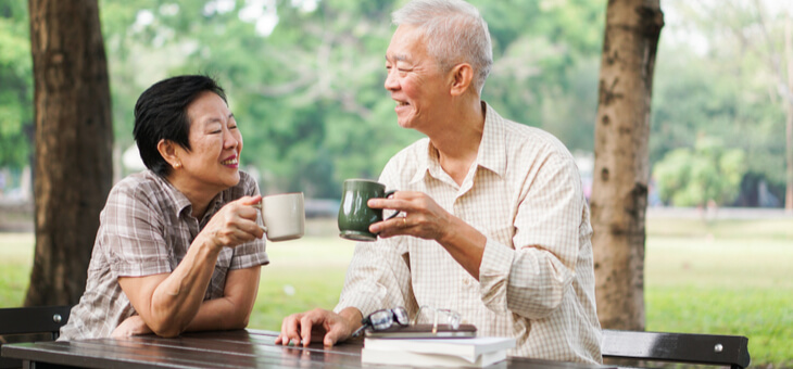 older couple drinking coffee in the park