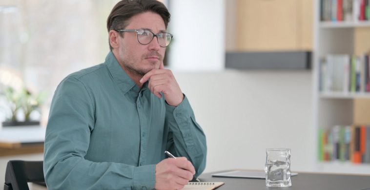 Middle aged man looks thoughtful as he considers canceling his health insurance