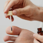 person applying wart remedy to toe