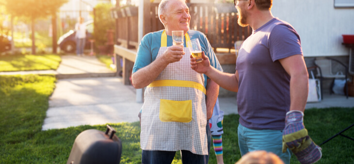 father and adult sun laughing at a barbeque