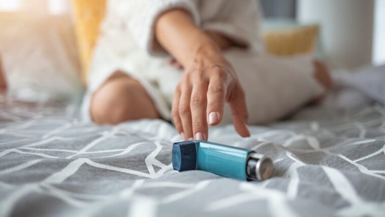 woman reaching for asthma inhaler