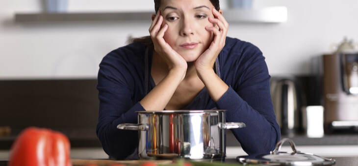 bored woman looking at food in kitchen