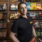 store owner standing in front of comic book display