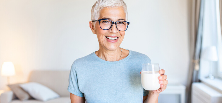 smiling mature woman holding glass of milk