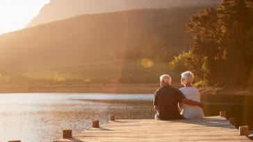 retired couple sitting on jetty at lake