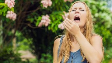 young woman sneezing outside