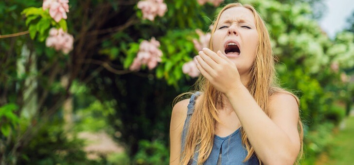 young woman sneezing outside