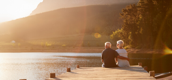 retired couple sitting on jetty at lake