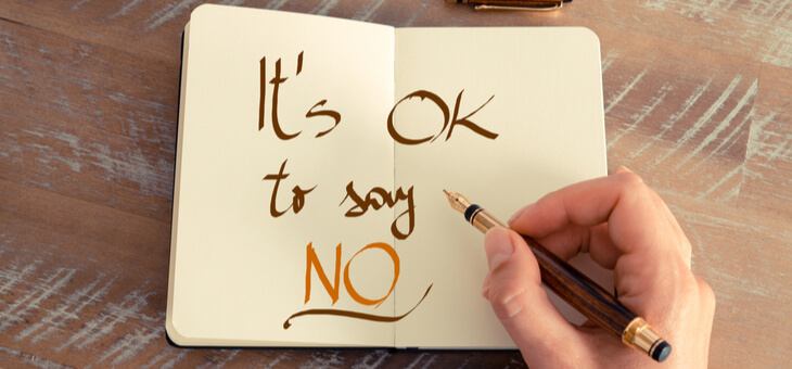 womans hand writing its ok to say no in a notebook