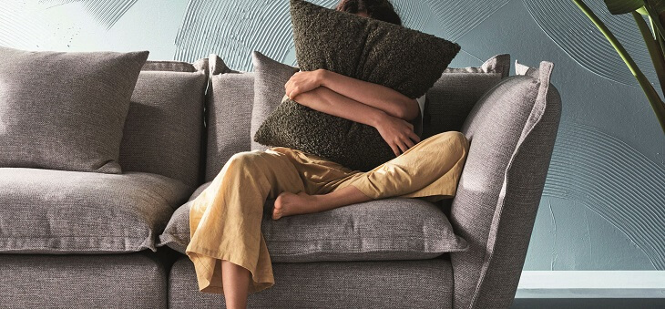 woman on couch hugging cushion to chest