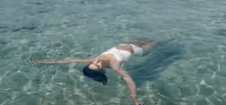 woman in white bathing suit floating on back in ocean