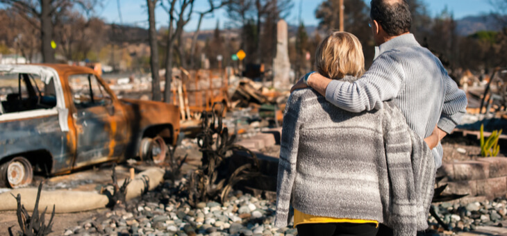 couple looking at burnt remains of their home