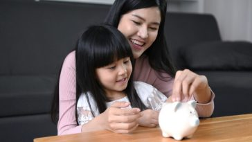 mother and child putting coins in piggy bank