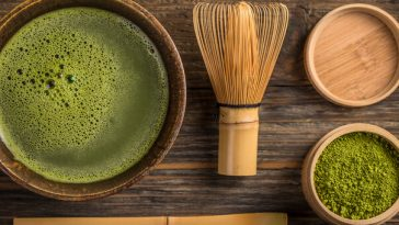 aerial view of cup of matcha tea and bamboo stirring utensils