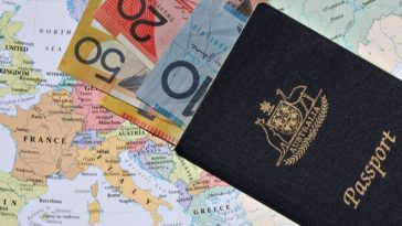 australian passport with australian banknotes inside on world map