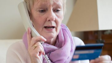 older woman holding credit card while speaking on phone