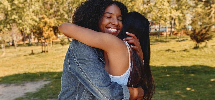 two women hugging in park