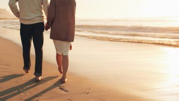 older couple walking on beach at sunset