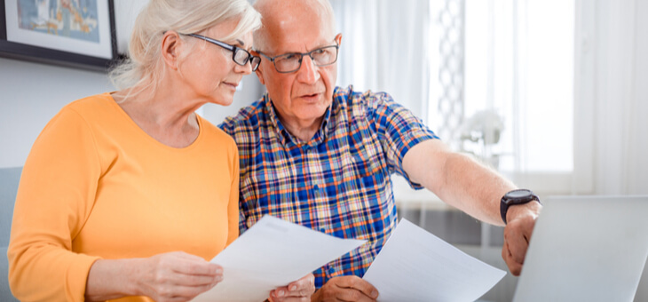 older couple on couch looking at bills