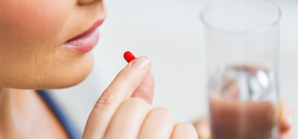 woman taking a red and white pill
