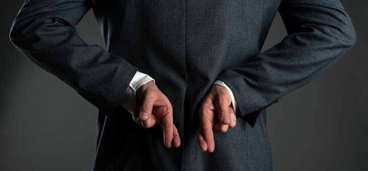 man in suit with fingers crossed behind back