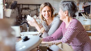 elderly woman speaking with adult daughter in kitchen