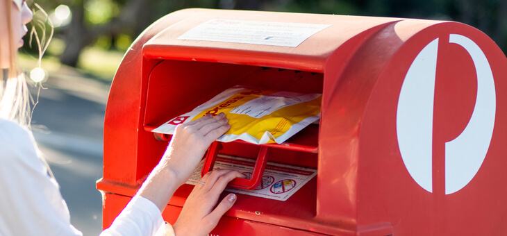 woman putting parcel in australia post box