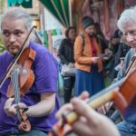 group of three men and one woman playing violins on belfast street