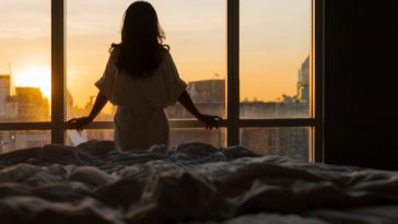 woman at hotel room window in dawn light