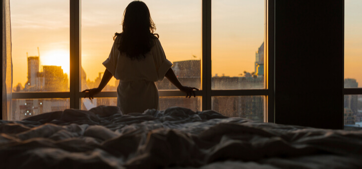 woman at hotel room window in dawn light
