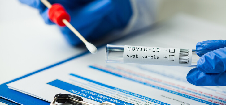 gloved hands holding covid pcr test and swab