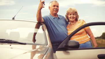 older couple leaning on car