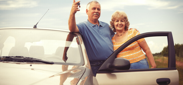 older couple leaning on car