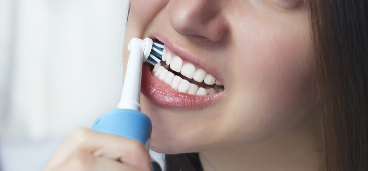 woman using electric toothbrush
