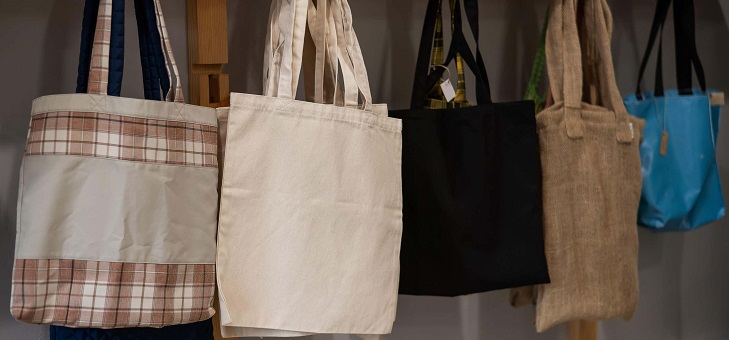 five cotton tote bags hanging on hooks