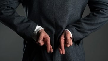 man in suit with fingers crossed behind back