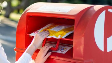 woman putting parcel in australia post box