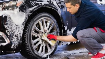 man washing car wheel with soapy water