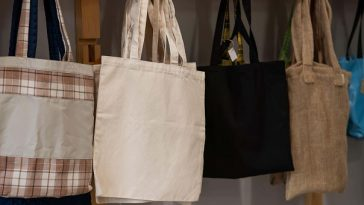 five cotton tote bags hanging on hooks