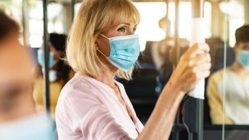older woman wearing protective face mask on crowded bus 730