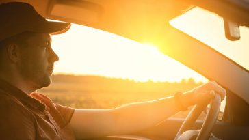 man driving with sun in window