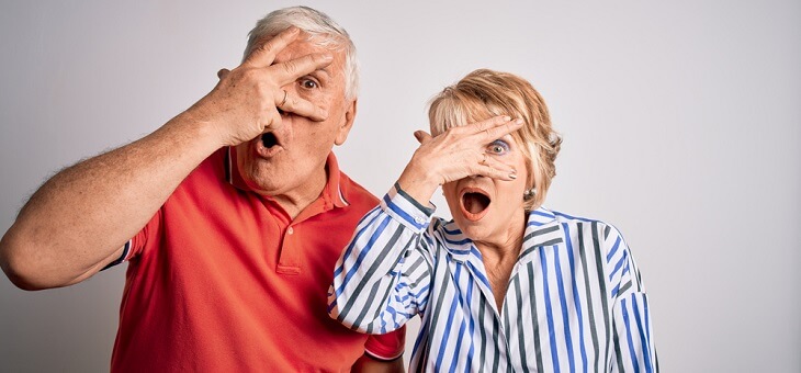 older couple both peeking through hand over face