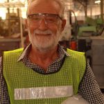 older man in high vis vest working in factory