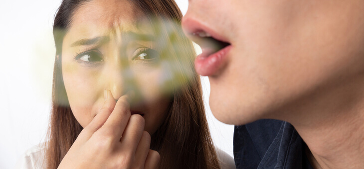 woman holding nose against another's breath